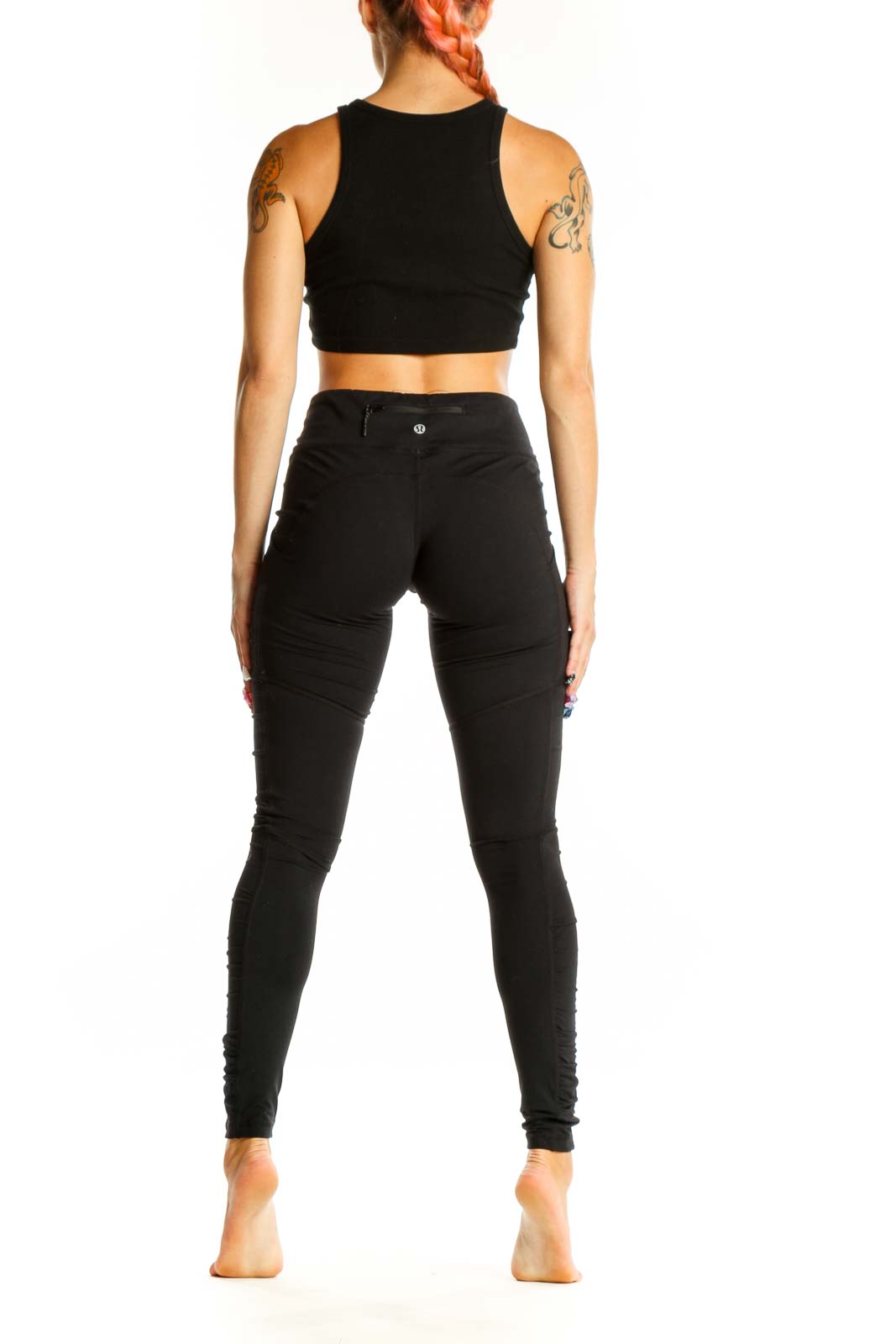 Side view of woman wearing black Lululemon high-waisted leggings and crop top