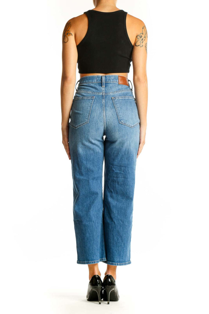 Side view of woman wearing Madewell blue wide-leg jeans and black crop top
