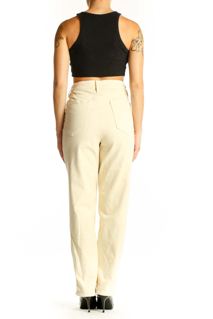 Side view of model wearing Athleta cream high-waisted straight leg jeans with black crop top