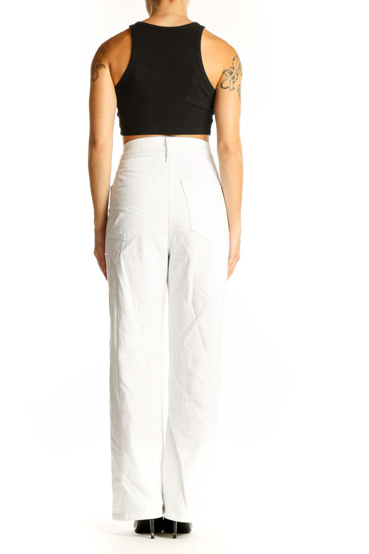 Side view of model wearing white high-waisted straight-leg jeans from J.Crew with black crop top