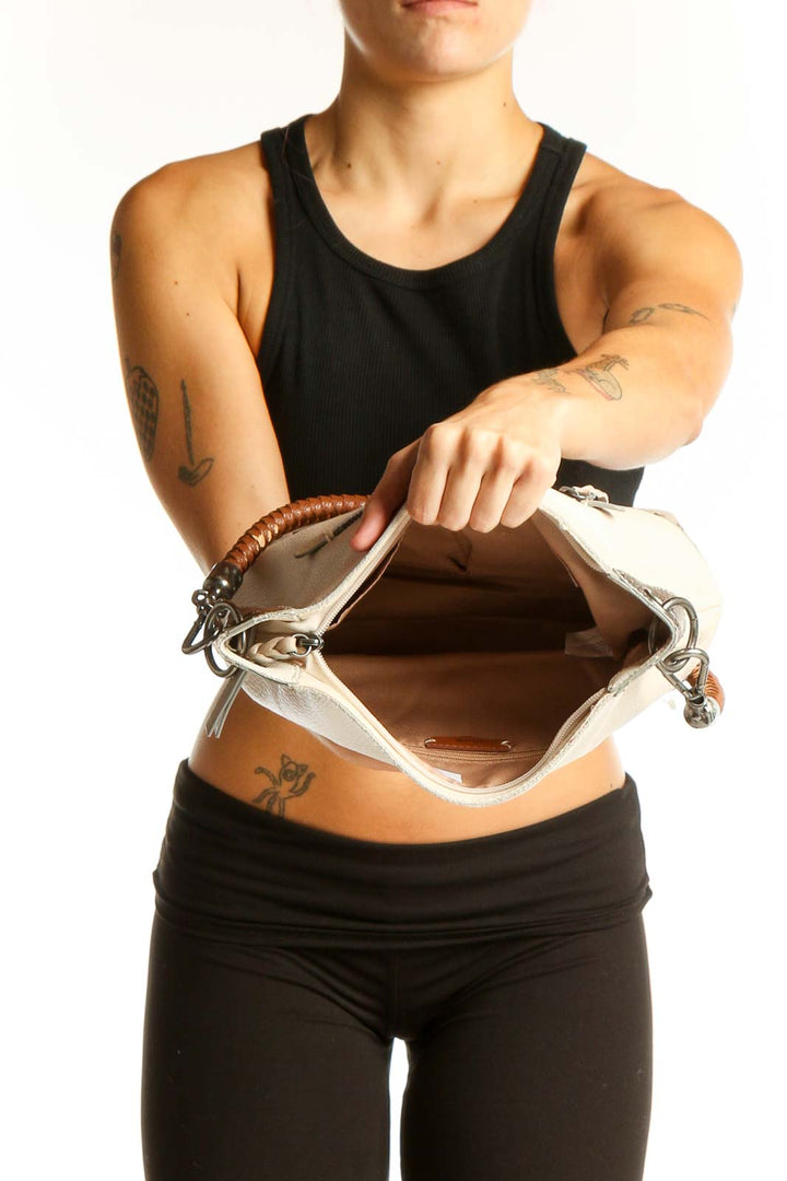 Side view of The SAK cream leather shoulder bag worn by model