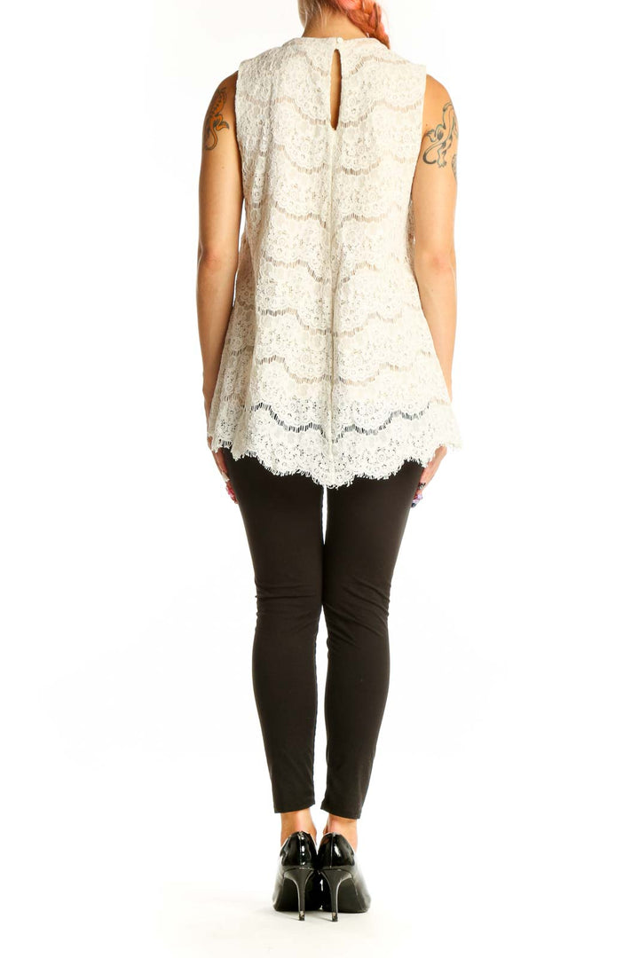 Side view of white lace sleeveless blouse showing scalloped hem