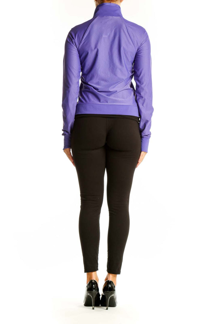 Side view of woman wearing purple Lululemon athletic jacket with black pants