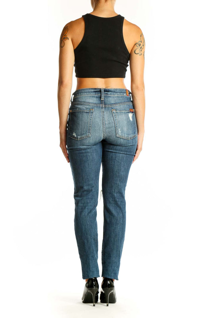 Side view of woman wearing 7 For All Mankind blue distressed straight leg jeans