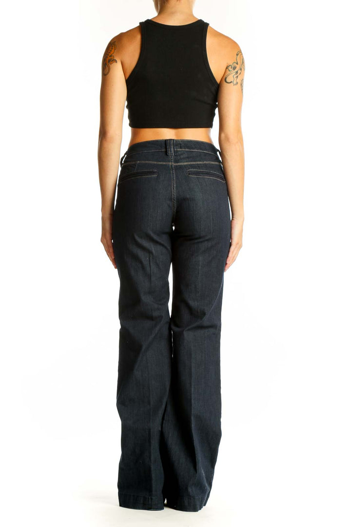 Side view of woman wearing dark blue wide-leg jeans with black crop top