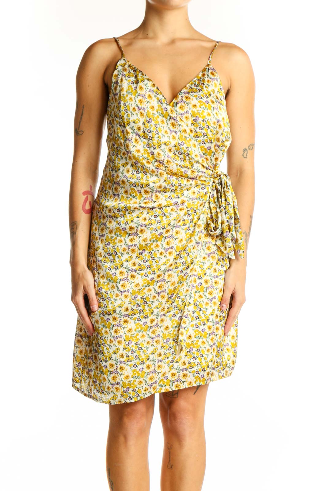 Front view of yellow floral wrap mini dress with spaghetti straps and side tie