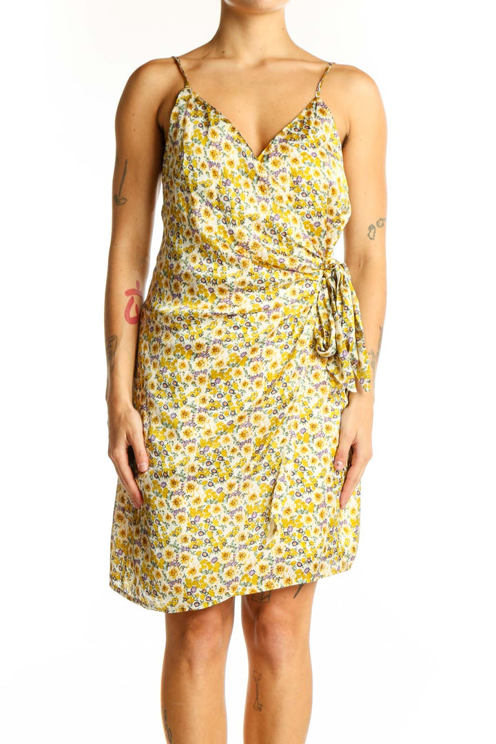 Front view of yellow floral wrap mini dress with spaghetti straps and side tie