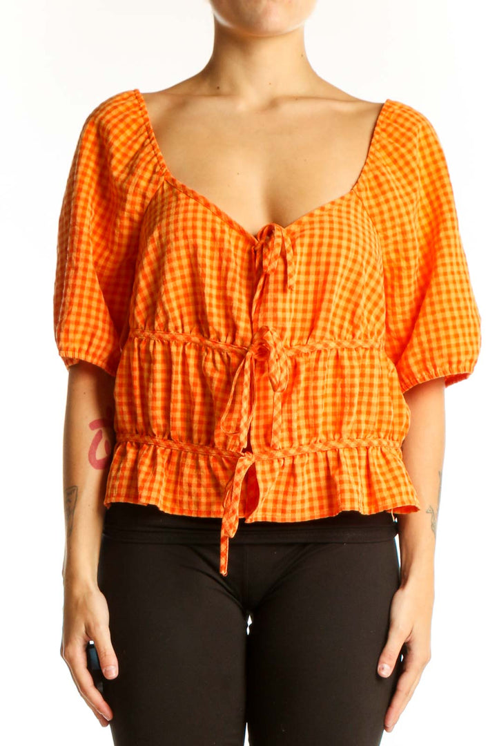 Front view of orange gingham crop top with puff sleeves and tie front