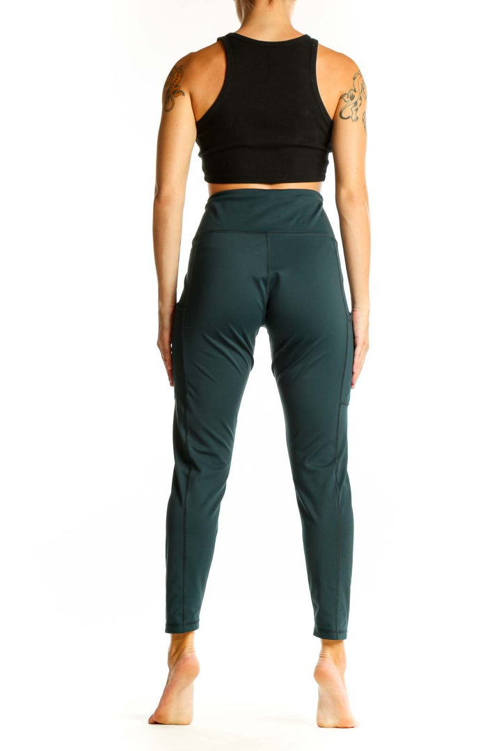 Side view of woman wearing dark green high-waisted activewear leggings and black crop top