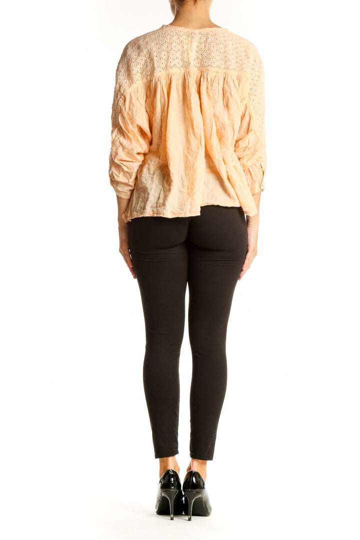 Back view of Free People peach eyelet lace blouse with black pants