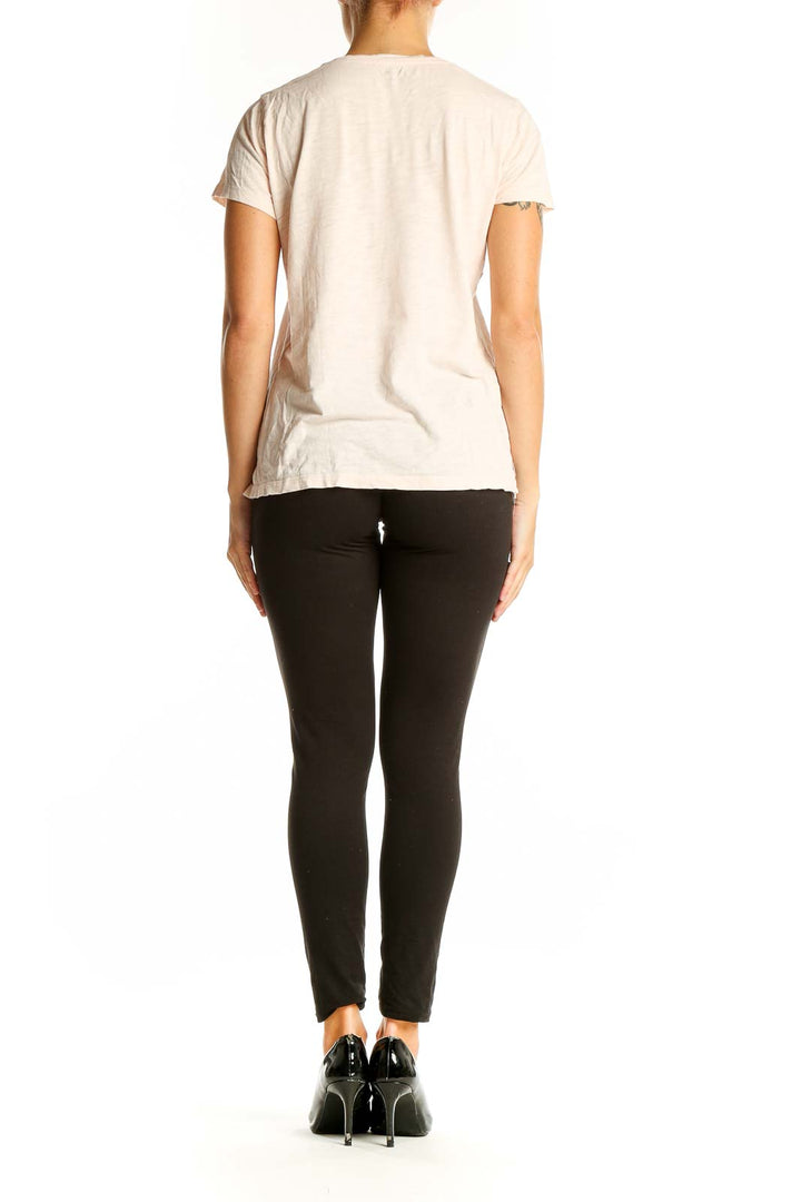 Side view of woman wearing Madewell blush V-neck cotton tee with black pants