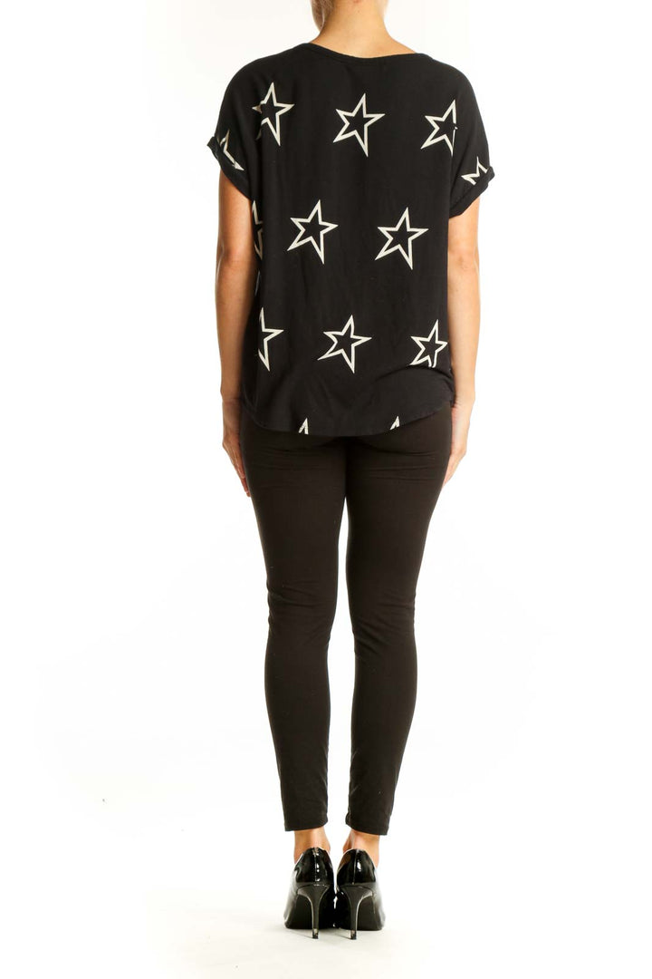 Side view of model wearing Buffalo by David Bitton Black Star Print Short Sleeve Top with black pants