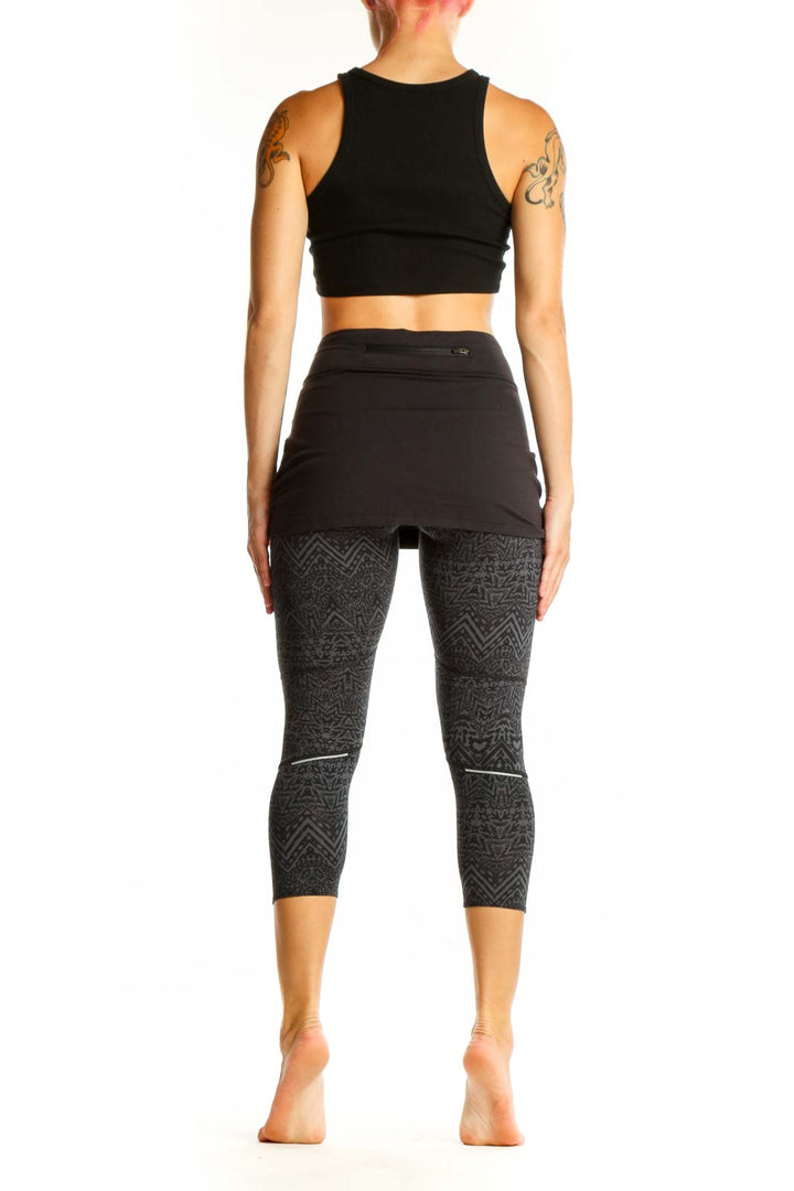 Side view of woman wearing Athleta black patterned capri leggings with attached skirt