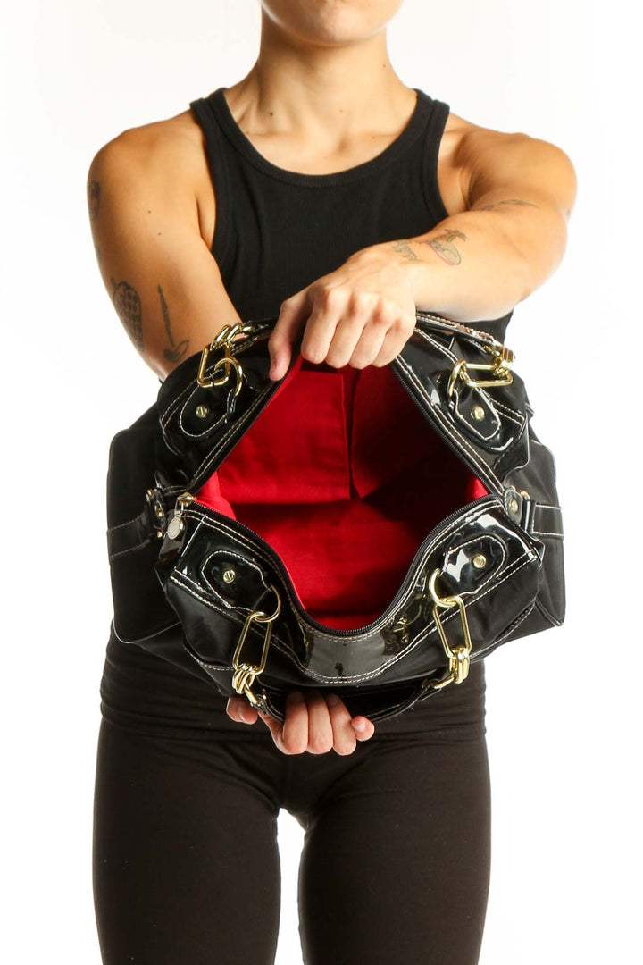 Model carrying Issac Mizrahi black shoulder bag with gold chain strap