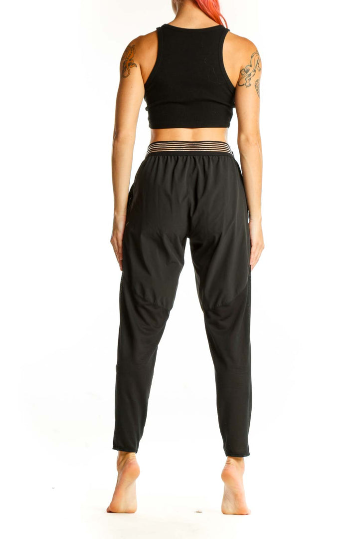 Side view of woman wearing black Nike athletic performance pants and crop top