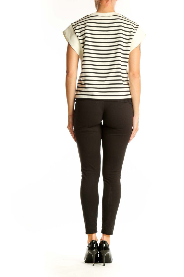 Side view of model wearing Spanx Black and White Striped Sleeveless Top with black pants
