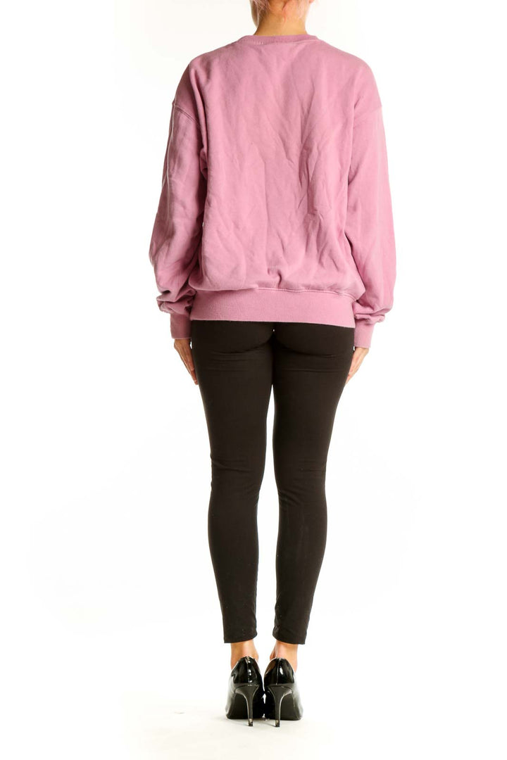 Side view of woman wearing Madewell pink sweatshirt with sun design
