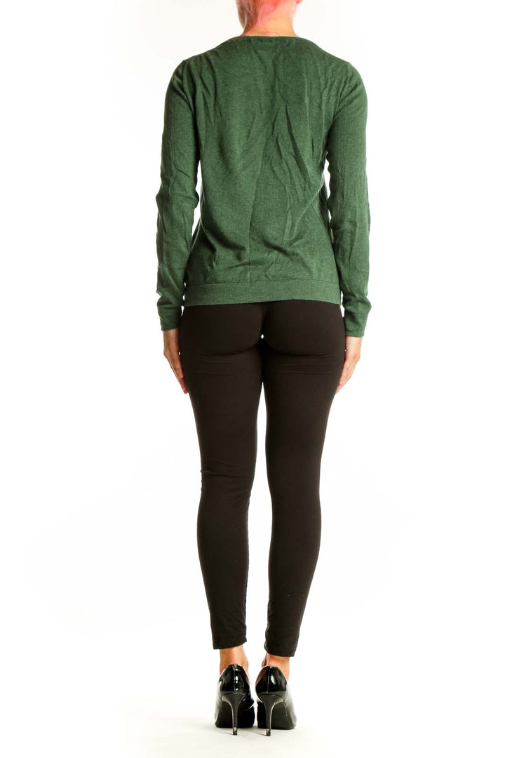 Side view of woman wearing J.Crew green cotton long sleeve top with black pants