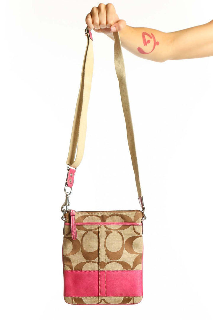 Front view of tan Coach crossbody bag with pink trim