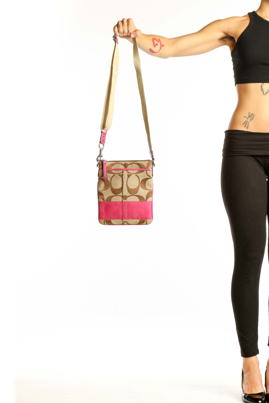 Front view of tan Coach crossbody bag with pink trim
