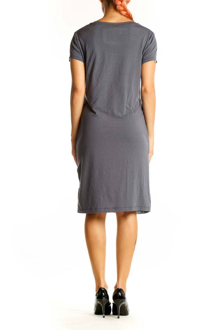 Side view of gray Halcyon dress showing ruching detail and asymmetrical hem