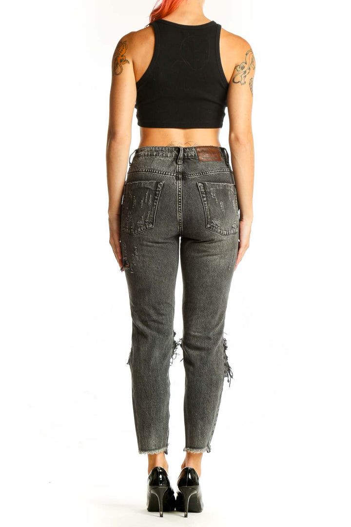 Side view of model wearing charcoal distressed cropped jeans with black crop top