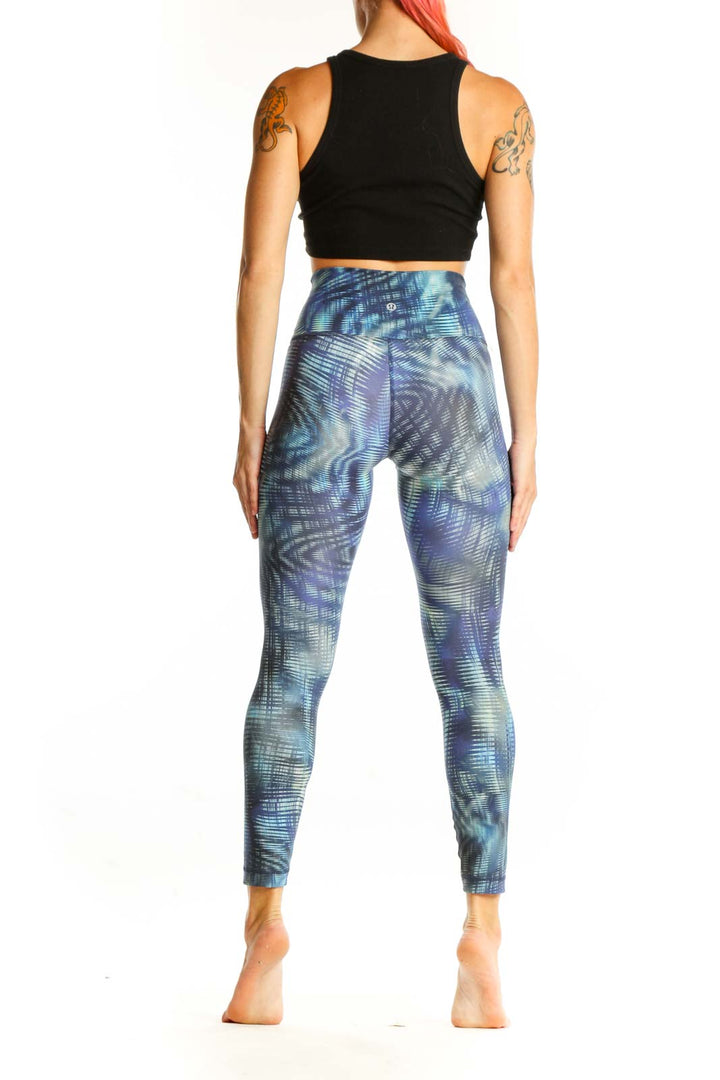 Side view of woman wearing Lululemon blue patterned high-waist activewear leggings with black crop top