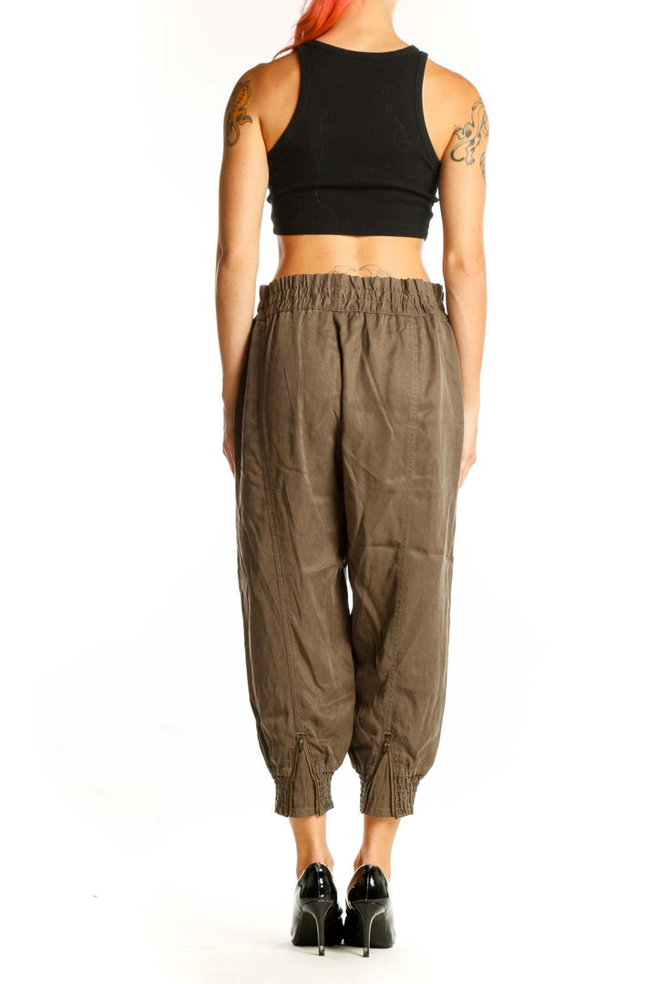 Side view of woman wearing olive Athleta Lyocell cropped jogger pants with black crop top