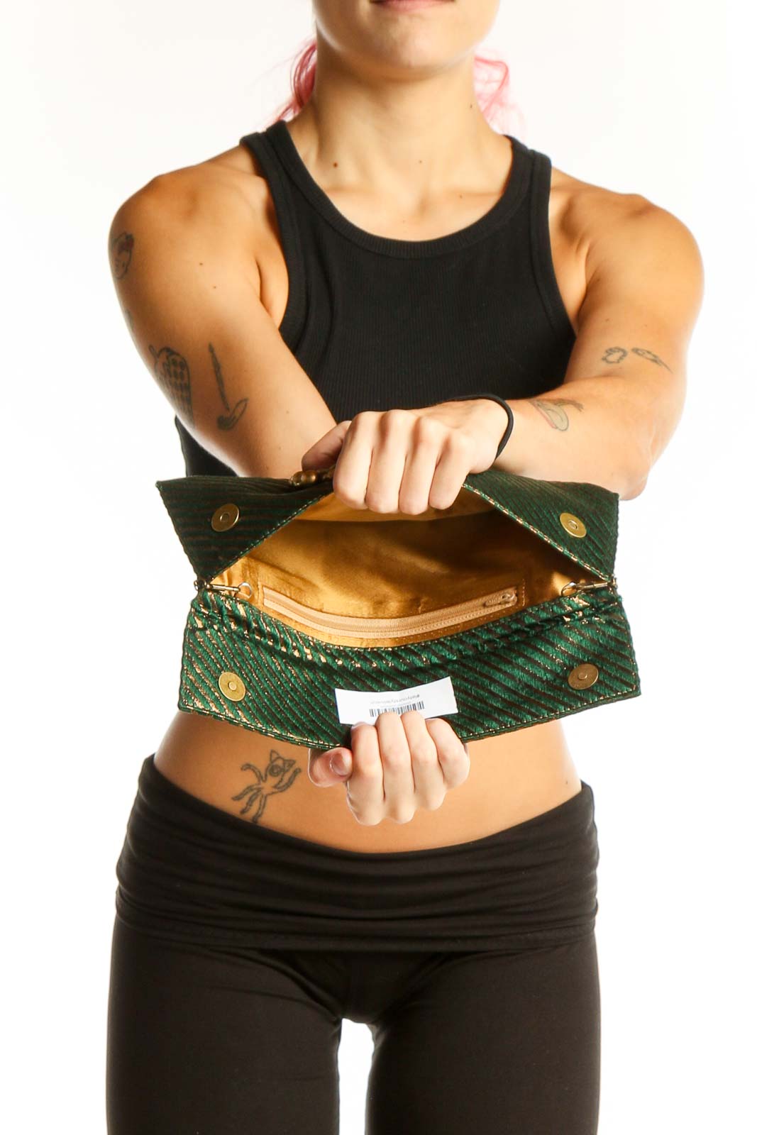 Model holding green metallic striped clutch against black outfit
