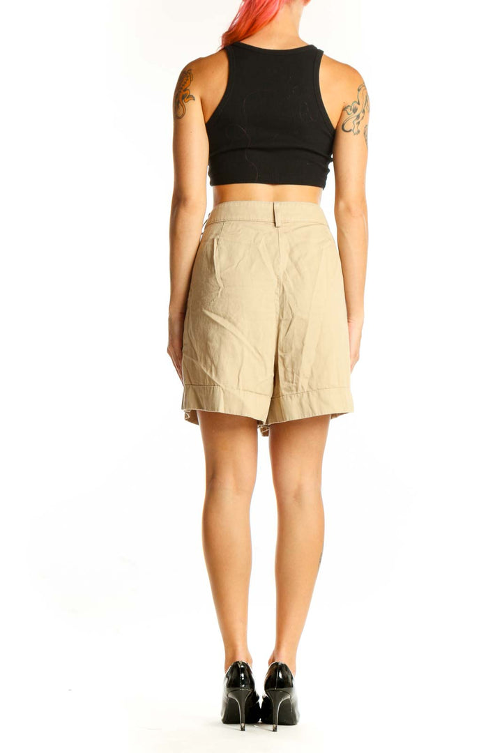 Side view of model wearing J.Crew beige cotton pleated shorts with black top