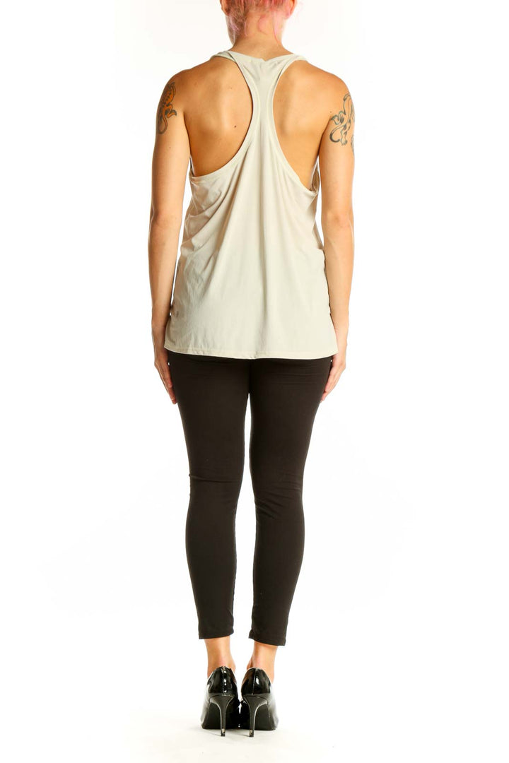 Side view of woman wearing beige Athleta sleeveless athletic tank top with black leggings