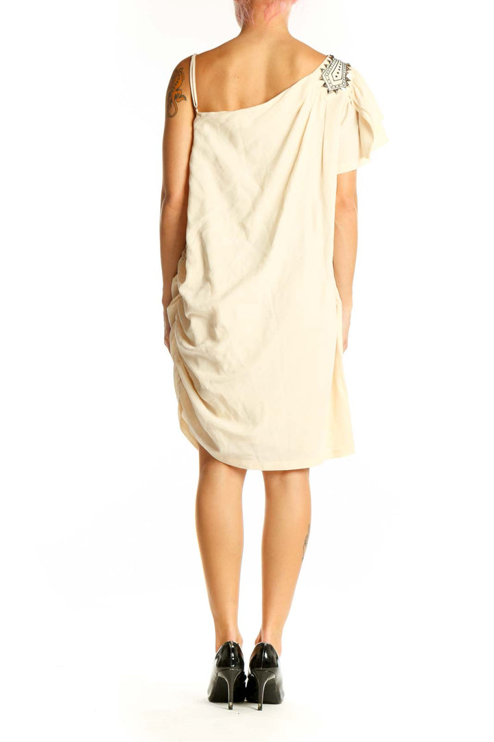 Side view of cream one-shoulder cocktail dress showing drape and fit