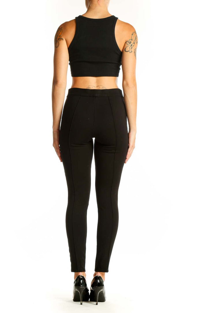 Side view of woman wearing black fitted pants with metallic stripes by Romeo & Juliet Couture