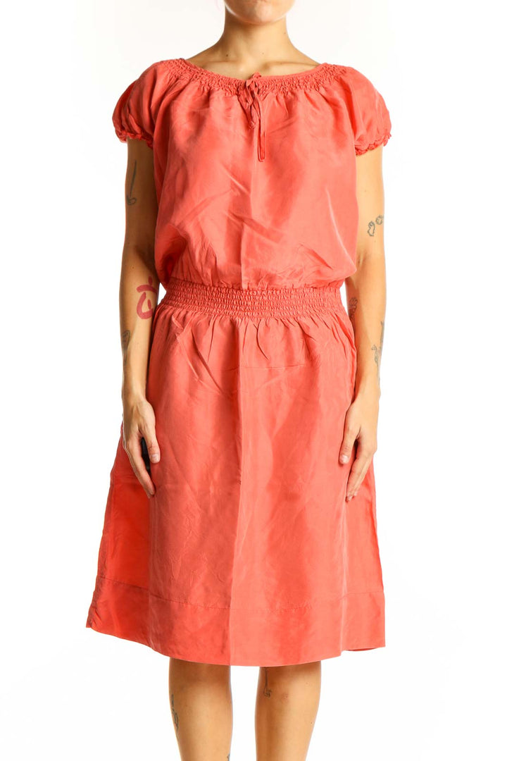 Front view of coral silk peasant dress with puff sleeves and smocked waist