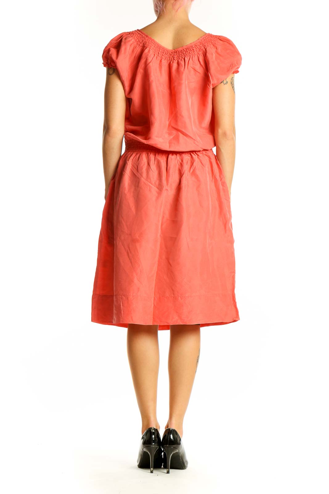 Side view of coral silk peasant dress showing flowy skirt and midi length