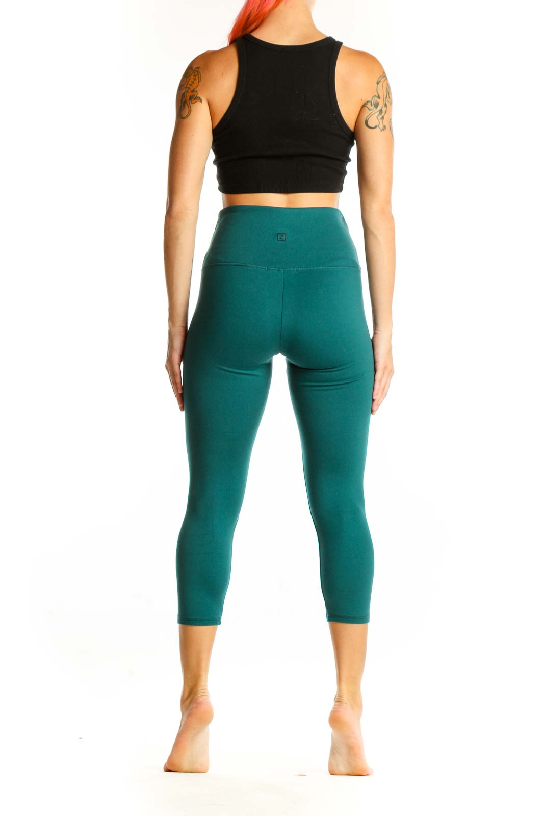 Side view of woman wearing teal Zobha capri leggings with black crop top