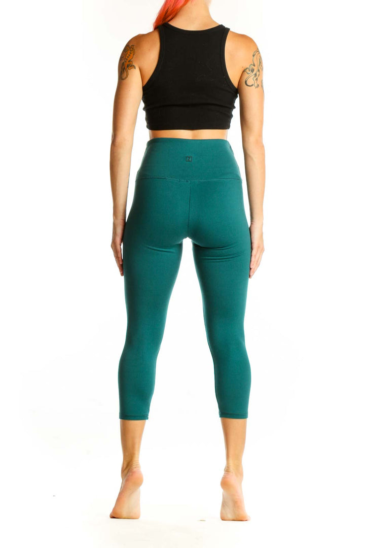 Side view of woman wearing teal Zobha capri leggings with black crop top