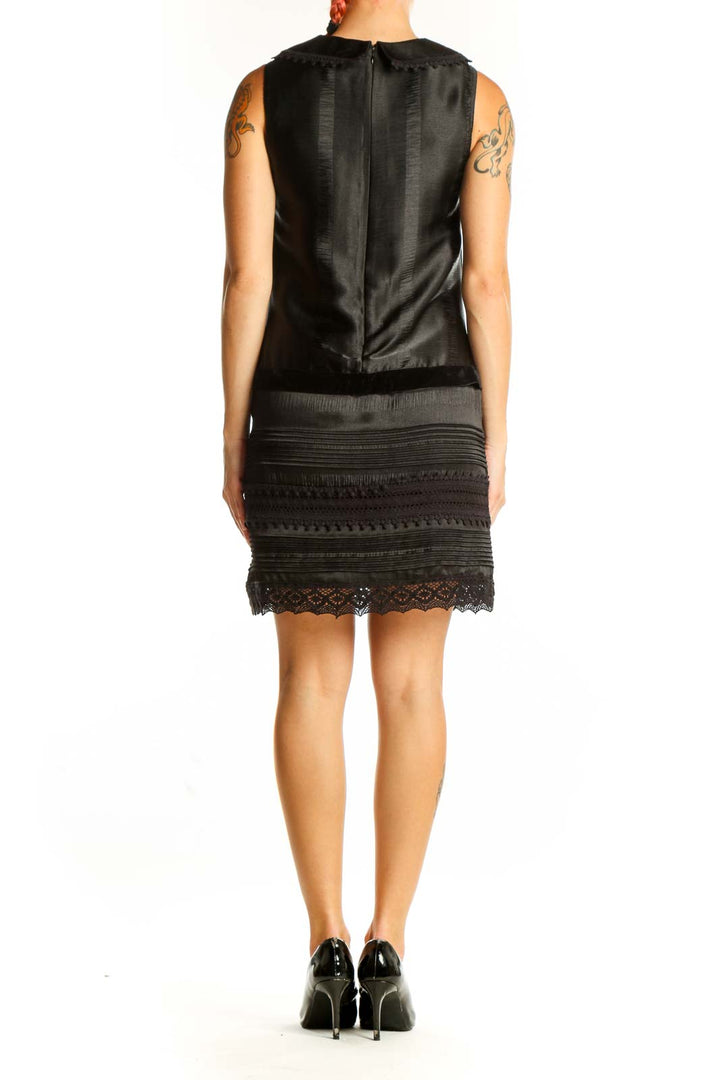 Side view of Anna Sui black vintage-inspired dress showing ornate buckle and lace hem