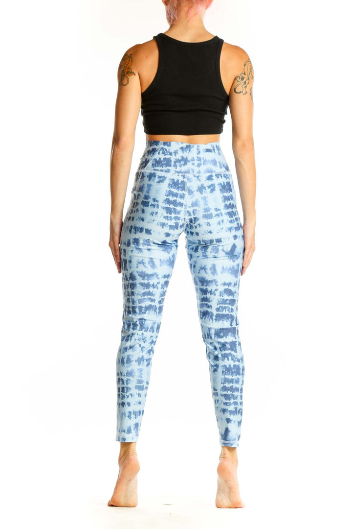 Side view of woman wearing blue tie-dye high-waisted activewear leggings with black crop top