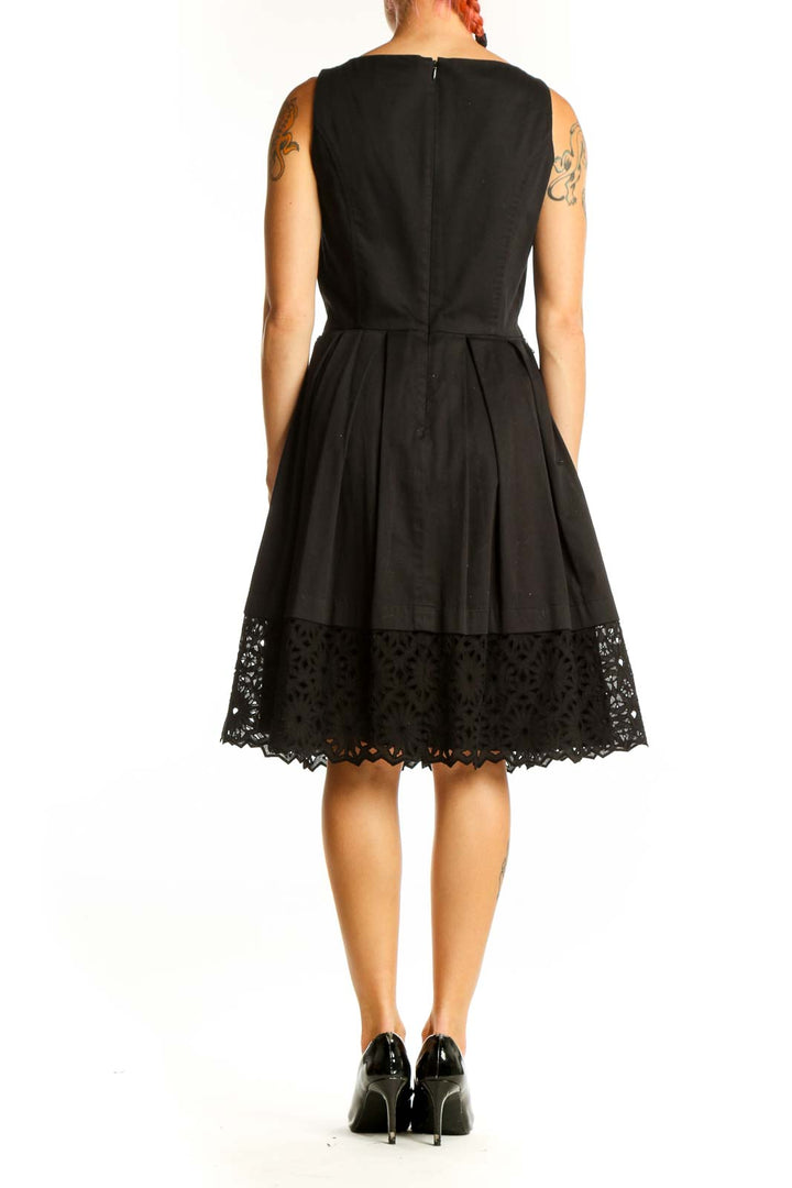 Side view of black sleeveless dress showing A-line silhouette and lace hem detail