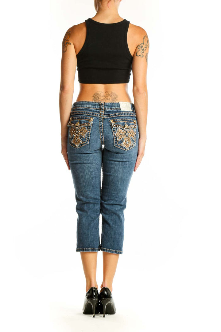 Side view of woman wearing LA IDOL blue distressed capri jeans and black crop top