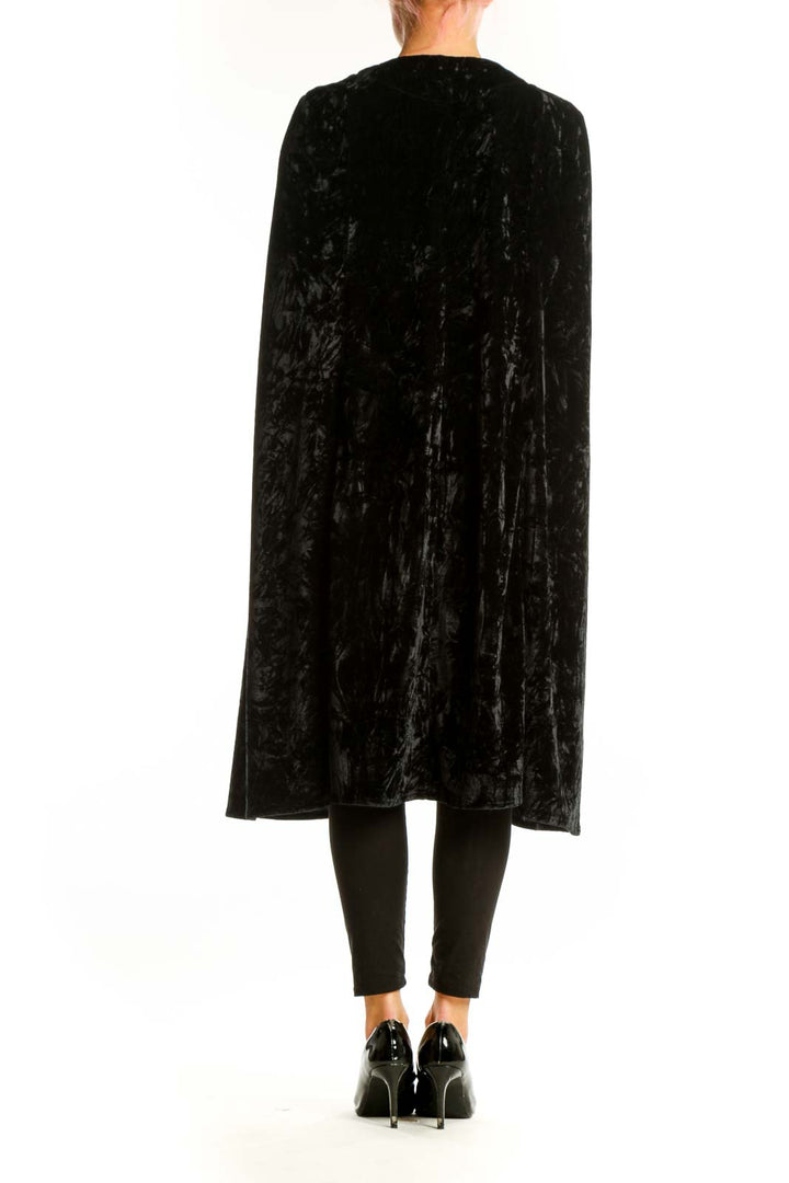 Side view of NastyGal black velvet cape jacket on model with heels