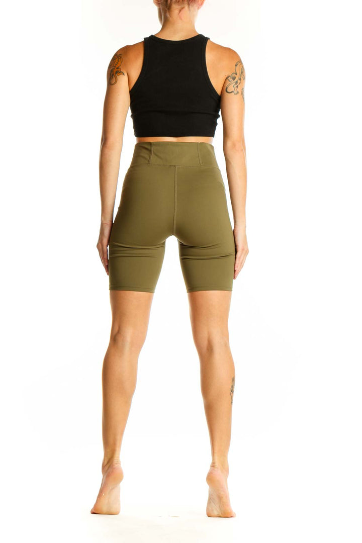 Side view of woman wearing olive Madewell high-waisted biker shorts with black crop top