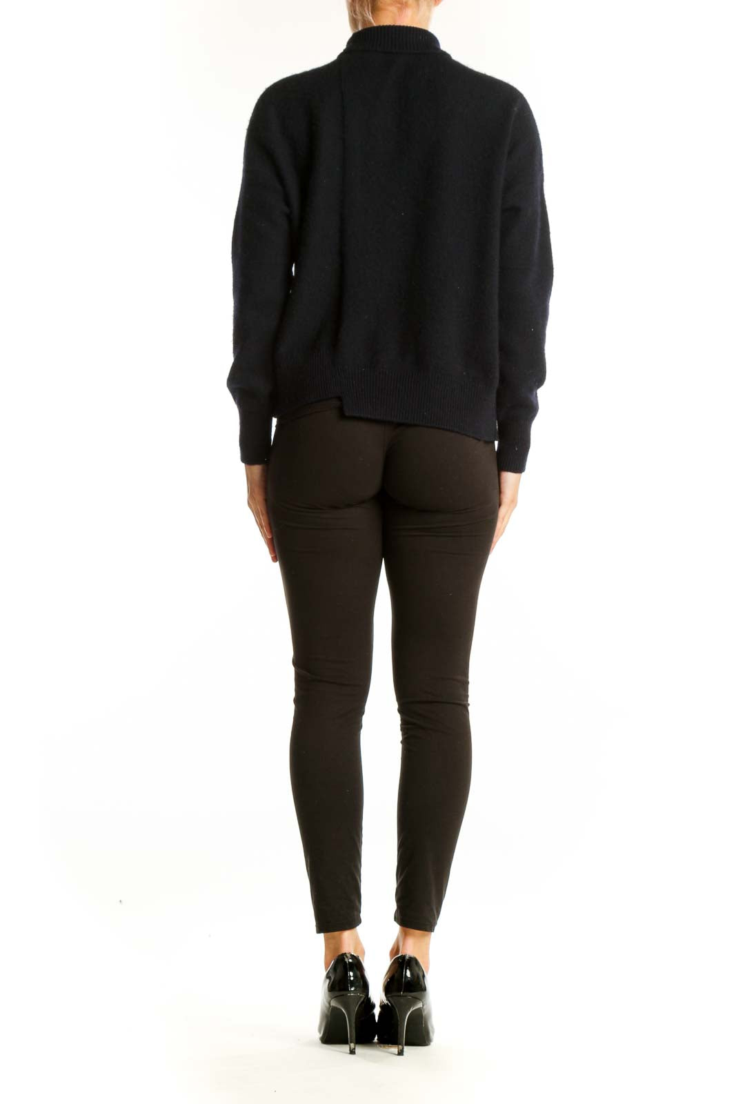 Side view of model wearing black Vince turtleneck sweater with dark pants