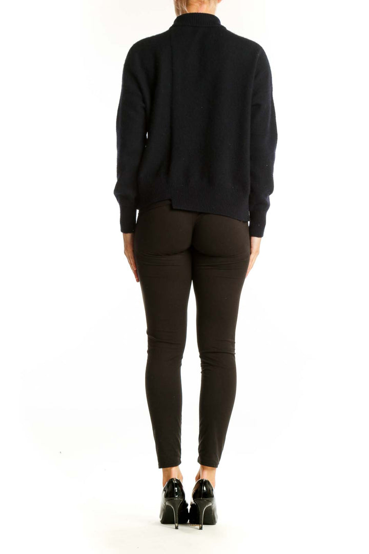 Side view of model wearing black Vince turtleneck sweater with dark pants