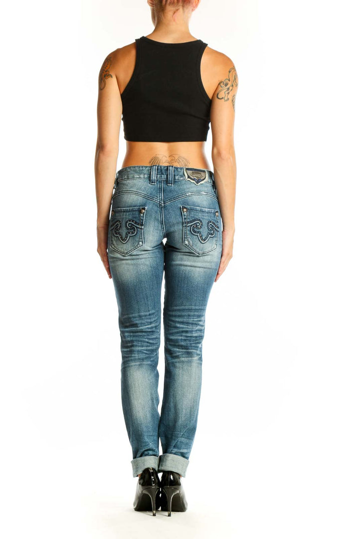 Side view of woman wearing ReRock for Express blue distressed skinny jeans with black crop top