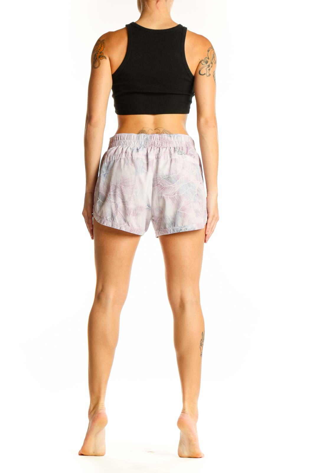 Side view of woman wearing pink floral print GapFit athletic shorts with black crop top