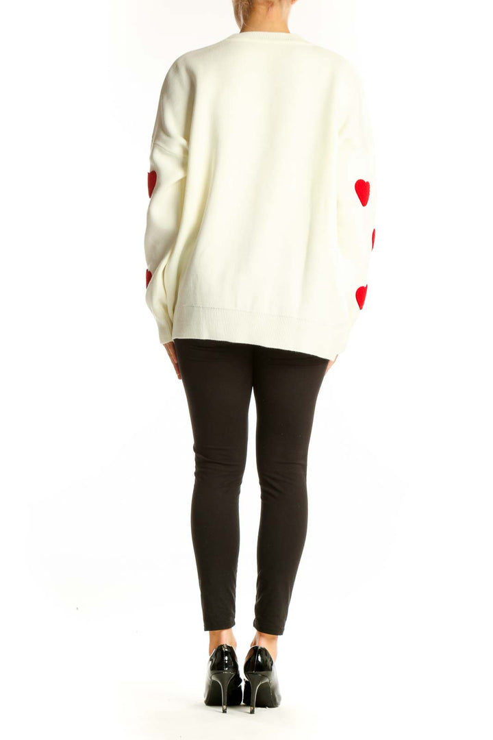 Side view of white oversized sweater with red heart pattern on model