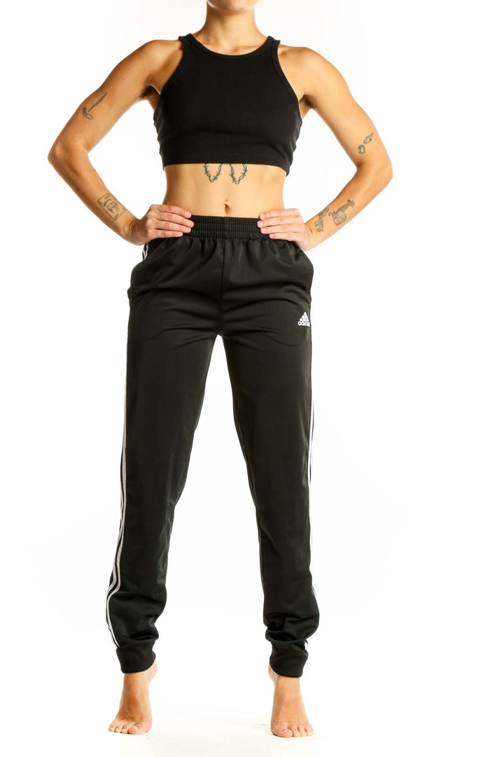 Front view of black Adidas track pants with white stripes