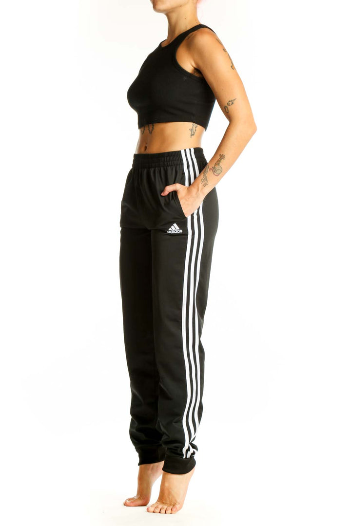 Front view of black Adidas track pants with white stripes